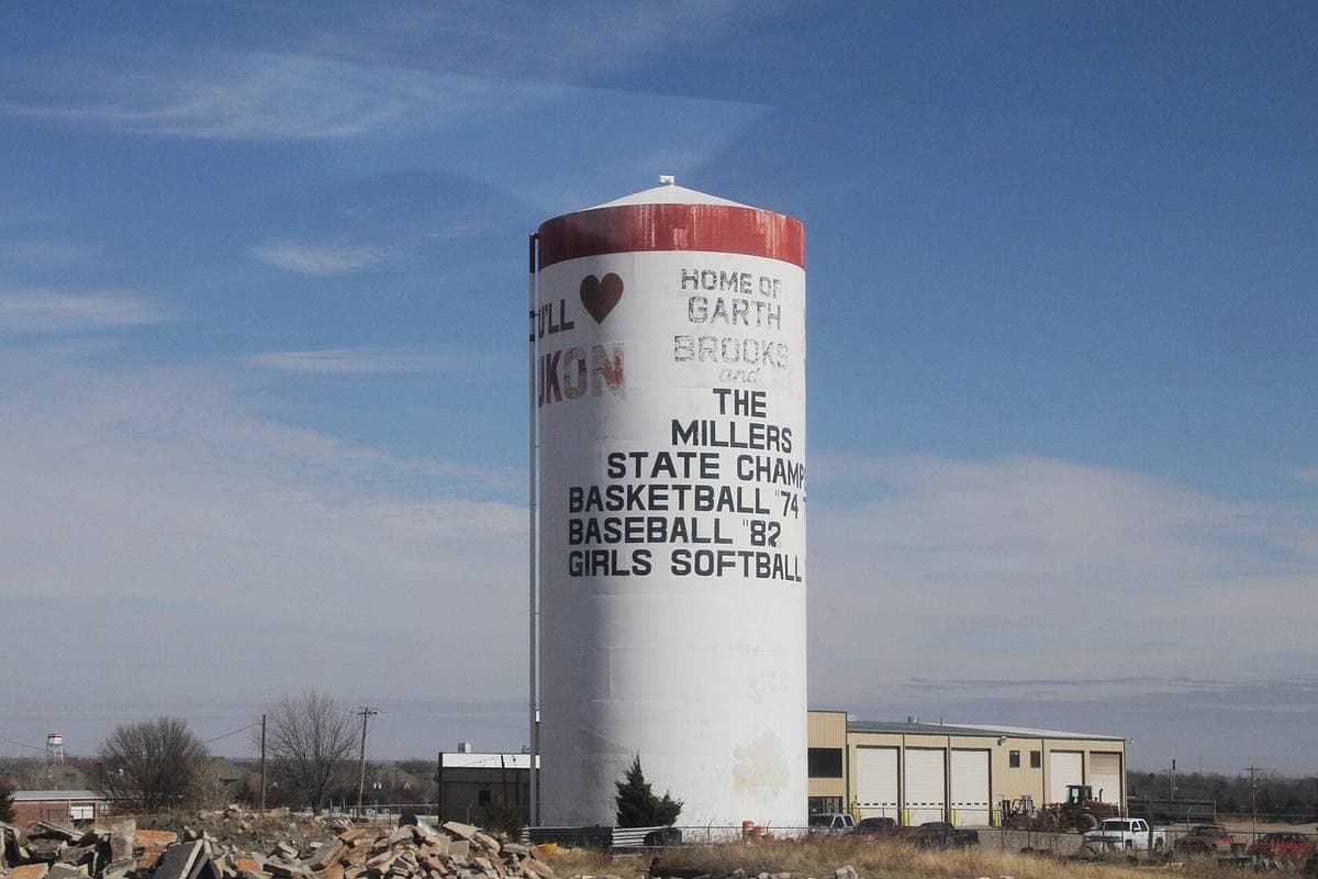 A pale water tower against the sky, lettered for Yukon and Garth Brooks