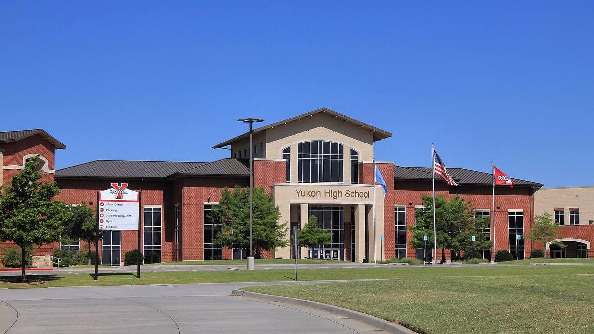 The brick front of Yukon High School under a blue sky