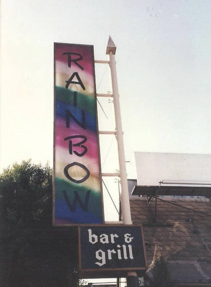 The Rainbow Bar and Grill's tall rainbow-striped sign against a pale sky in 1991