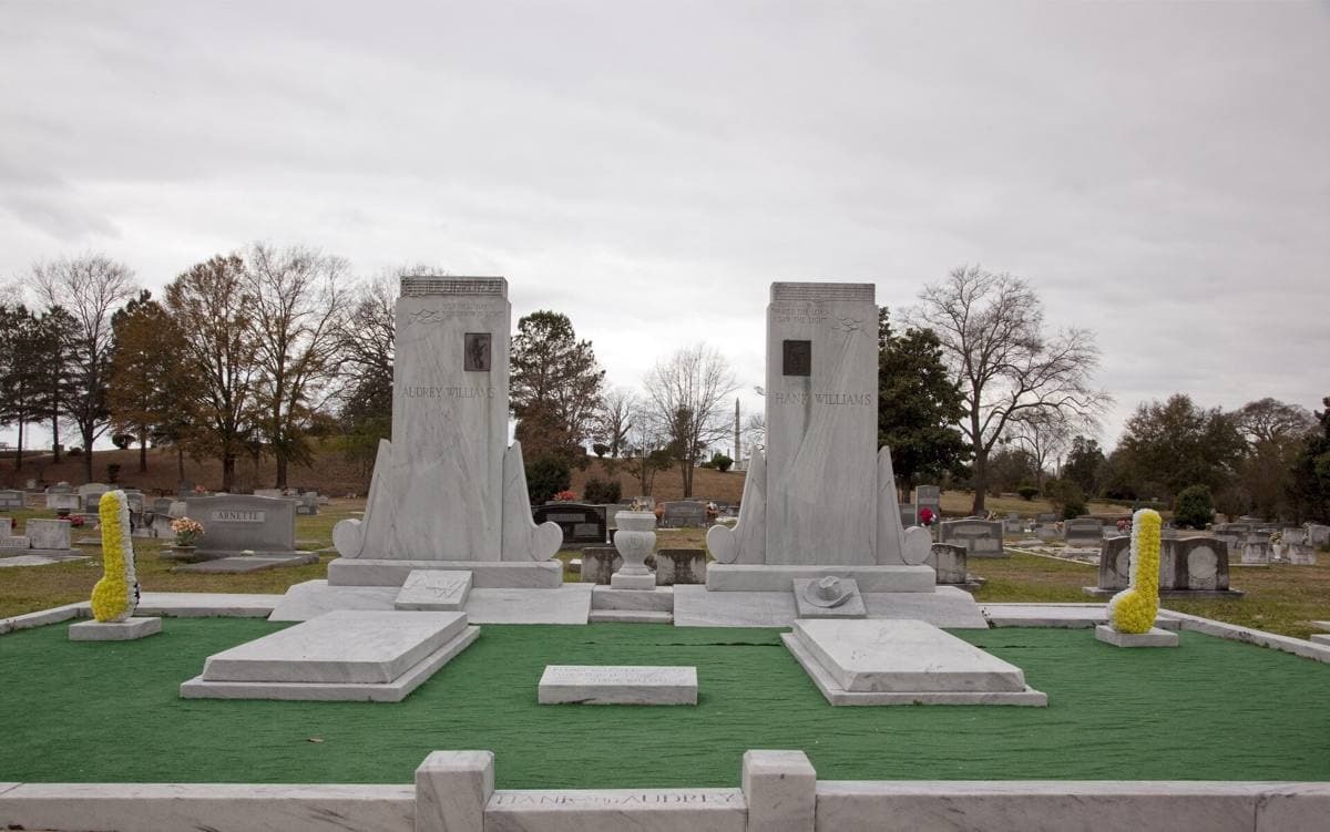 Two pale marble memorials on a raised plot of green artificial turf