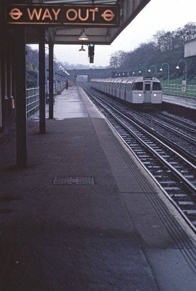 An empty Underground platform with a Way Out sign, in muted colour
