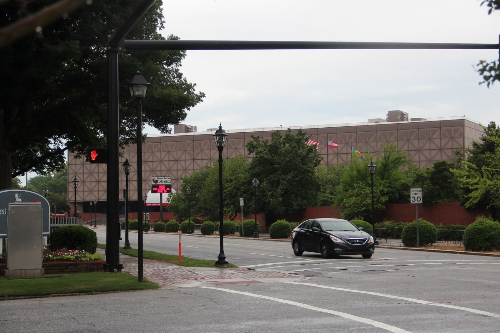 A low brown arena building seen across a street junction