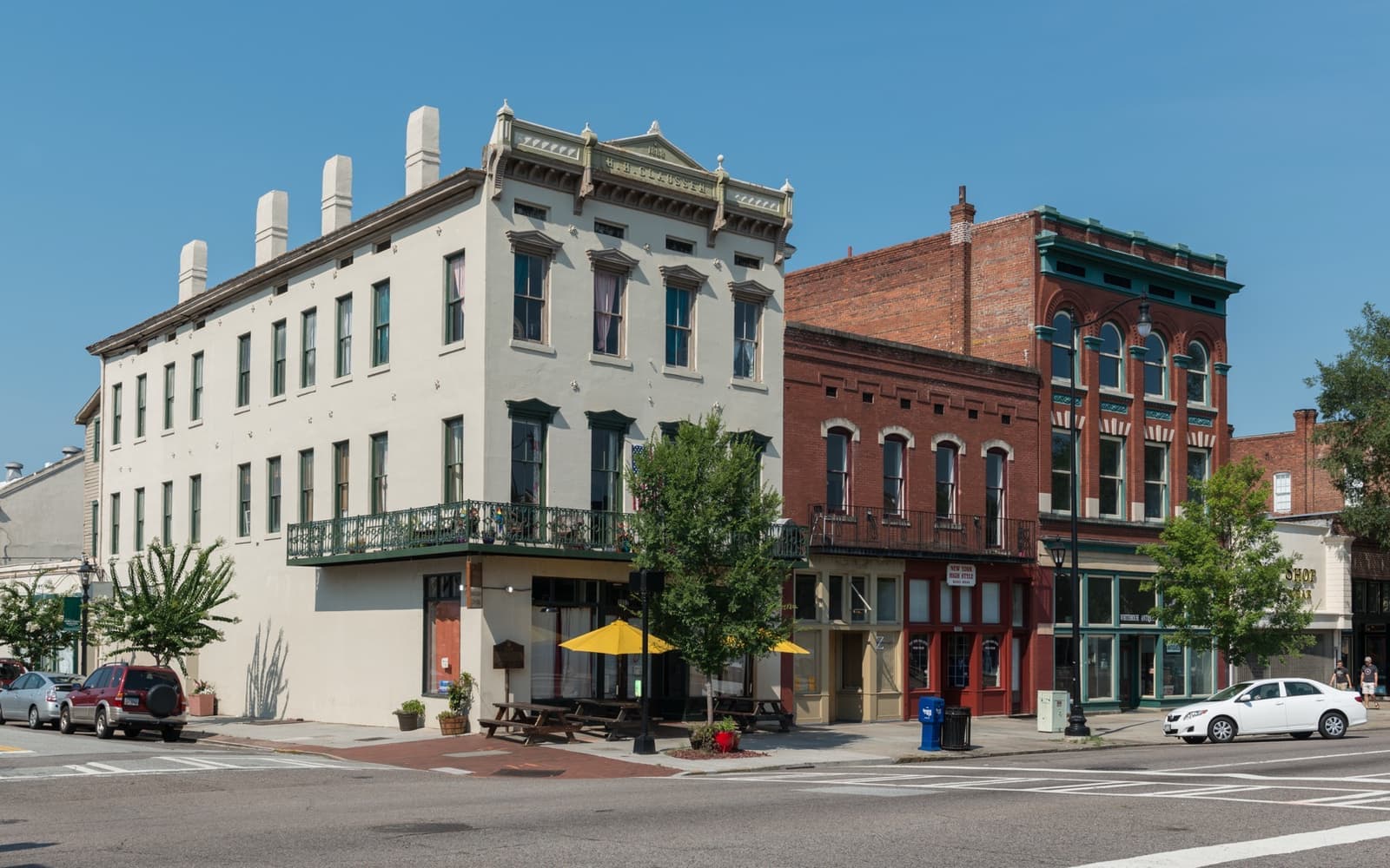 Three restored nineteenth-century buildings on a corner of Broad Street, with yellow umbrellas