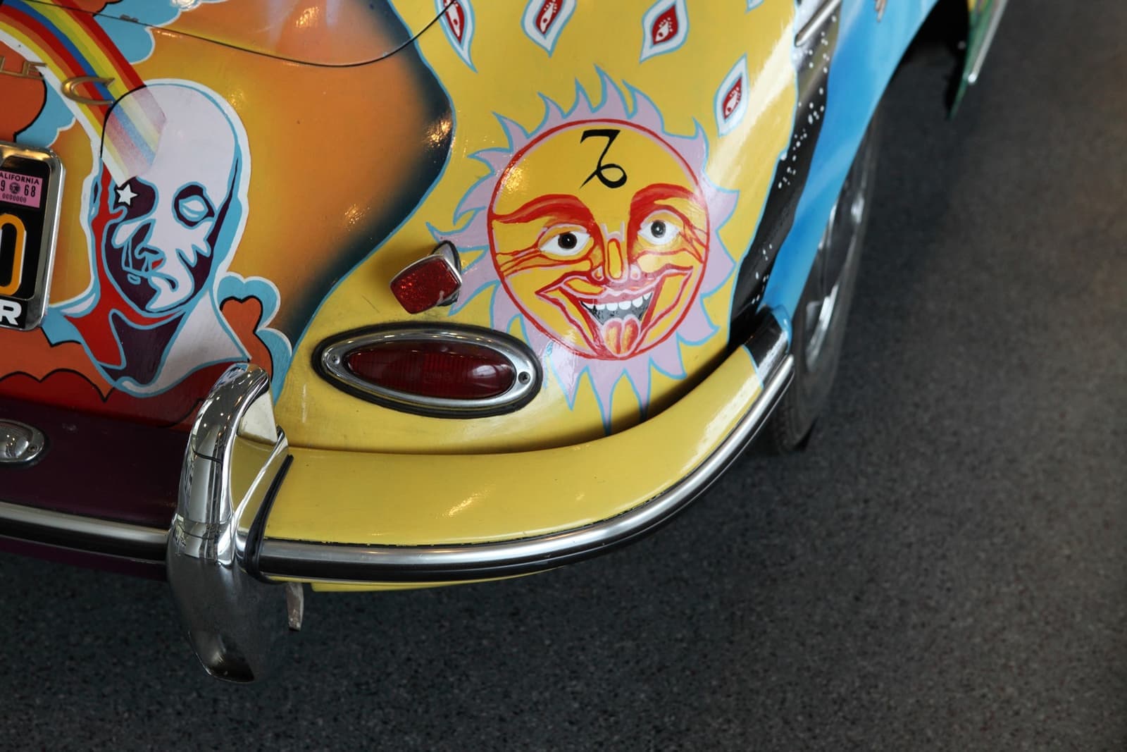 A painted sun face with the Capricorn symbol on the yellow rear wing of the car, beside a blue-faced figure