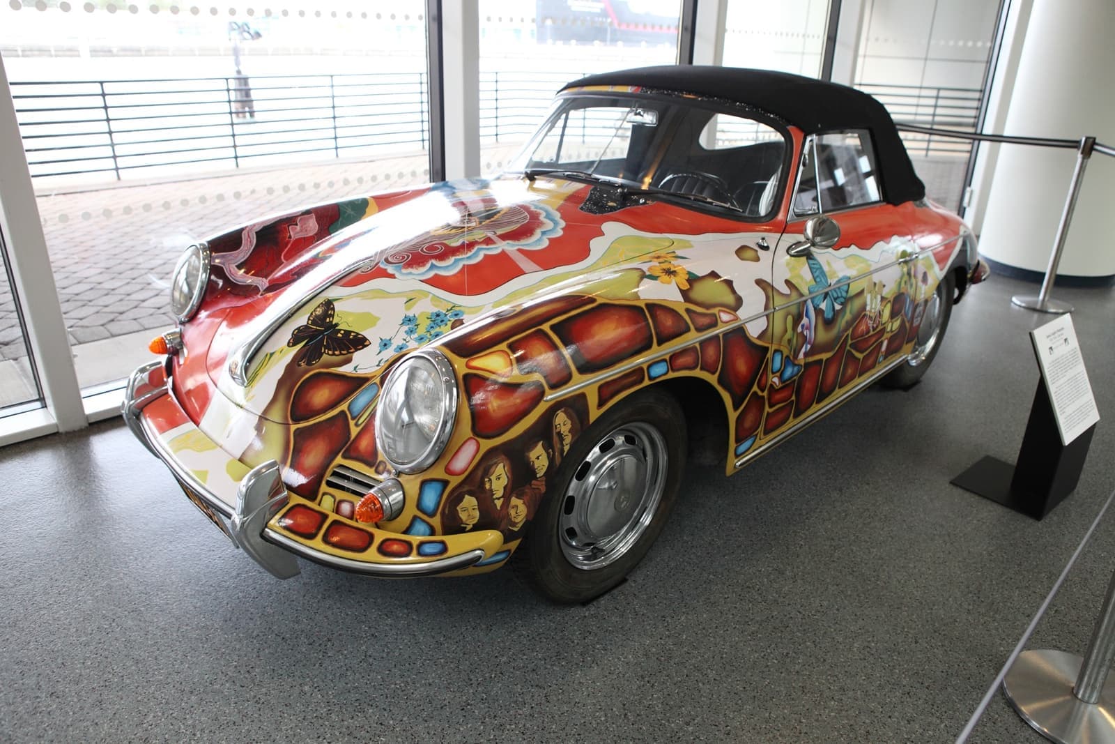 A Porsche convertible covered nose to tail in painted swirls, butterflies, faces and a red and gold base coat