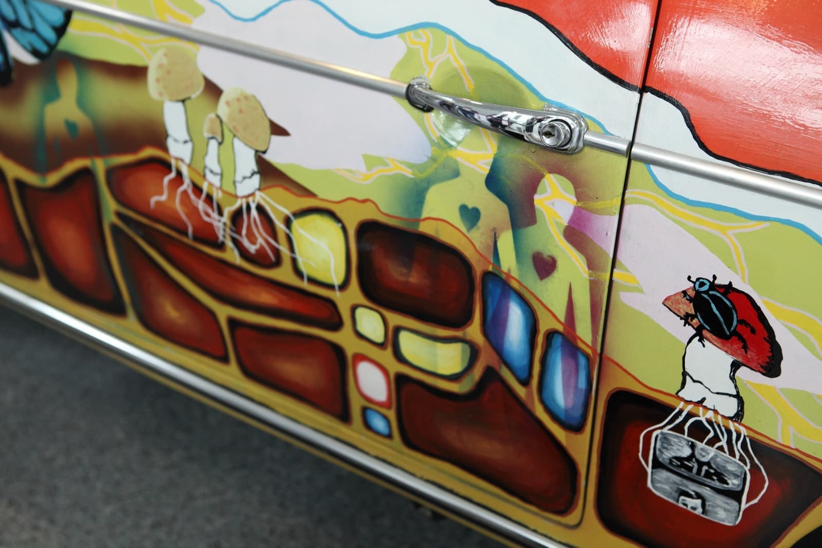 Close view of the car’s side panel painted with small figures, coloured shapes and a ladybird