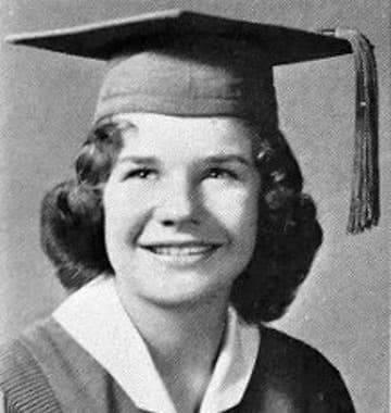 Yearbook portrait of a smiling teenage Janis Joplin in a mortarboard and gown