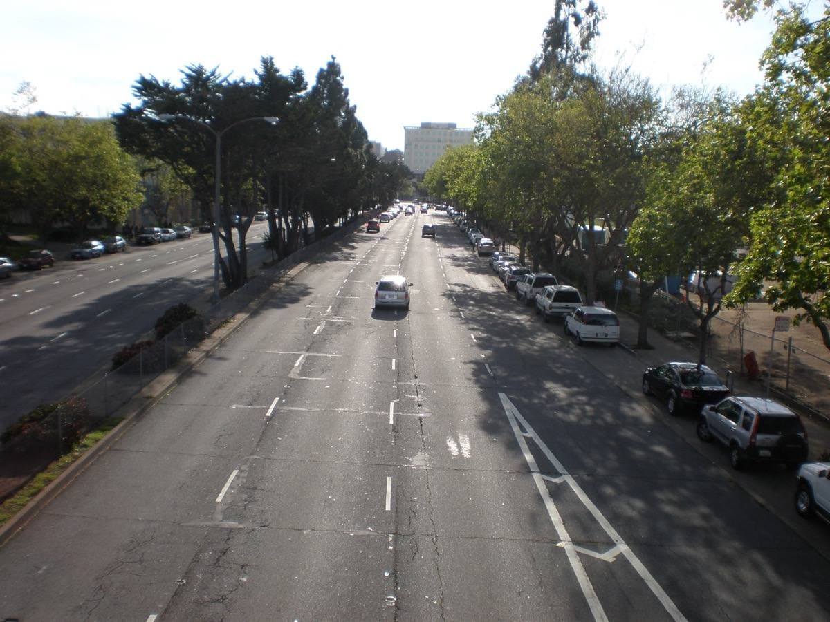 A wide boulevard lined with trees, seen from a footbridge