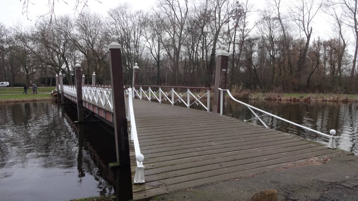A small bridge over the edge of a lake in a park