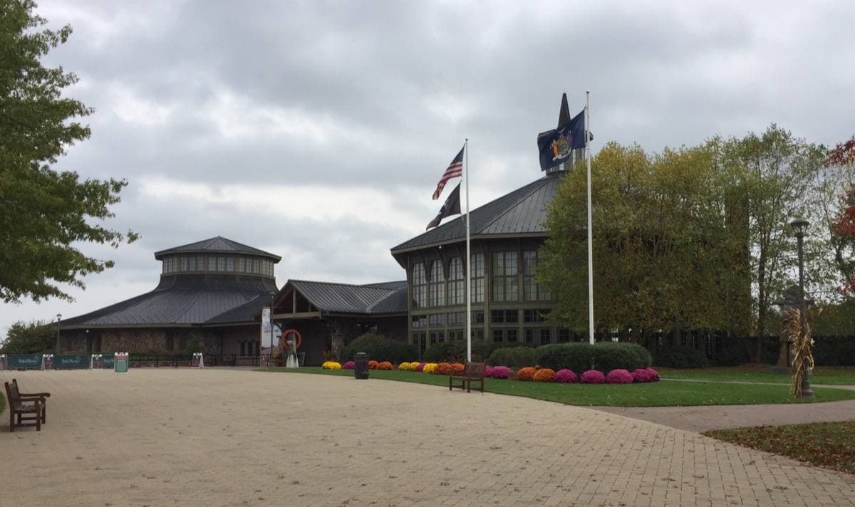 A low museum building with a flagpole and a gravel forecourt