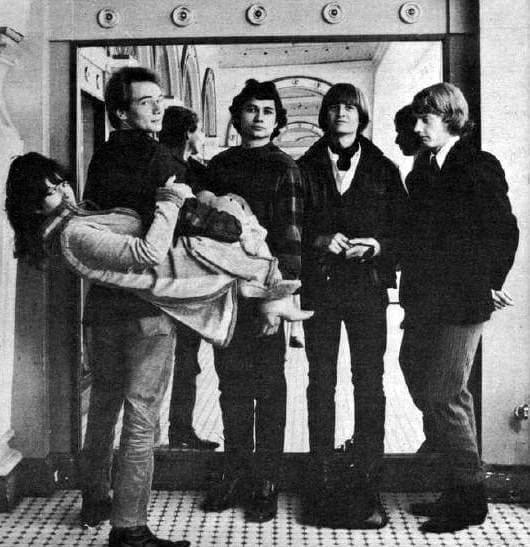 Five young musicians outdoors, one woman being carried in a man’s arms