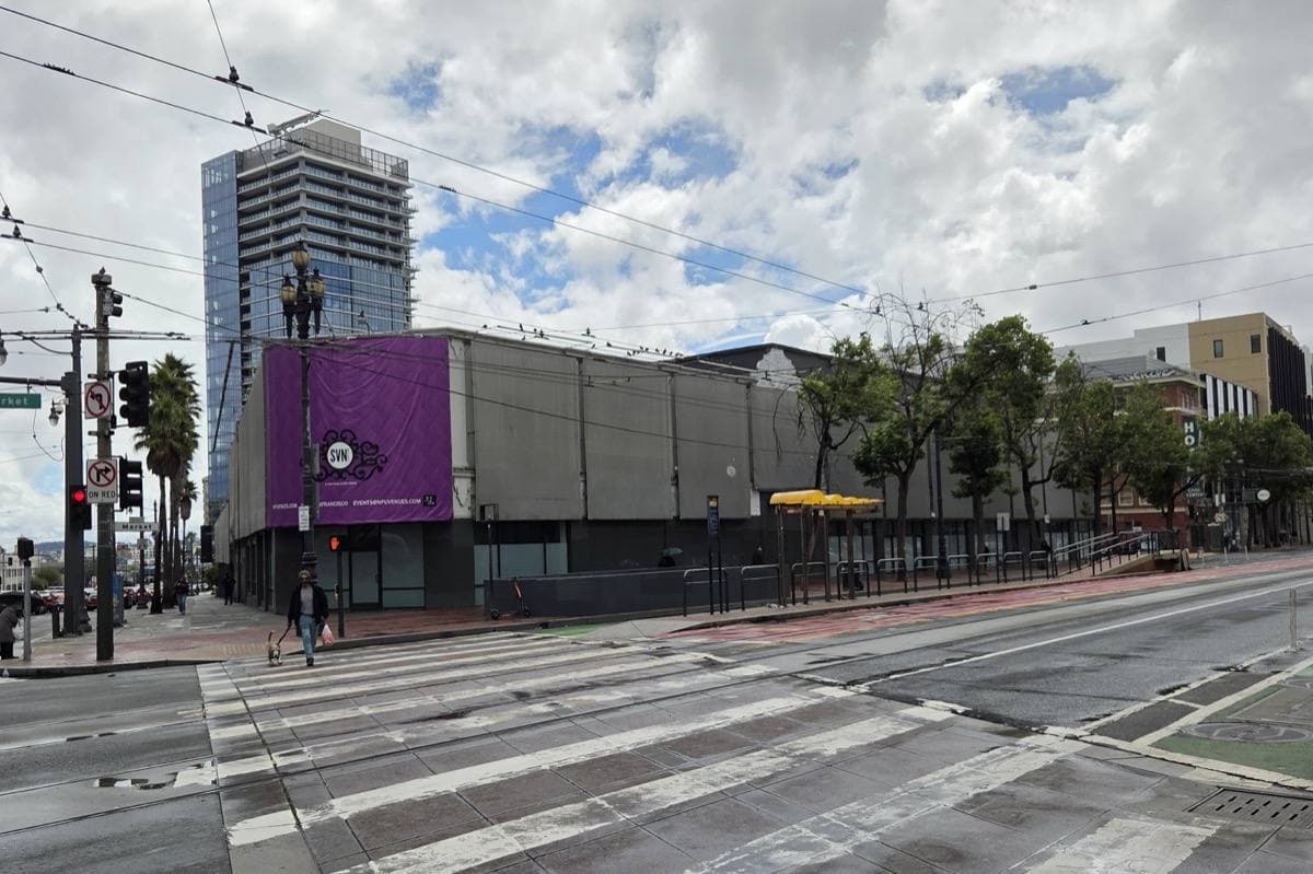 A long low building with purple banners on a wide street corner