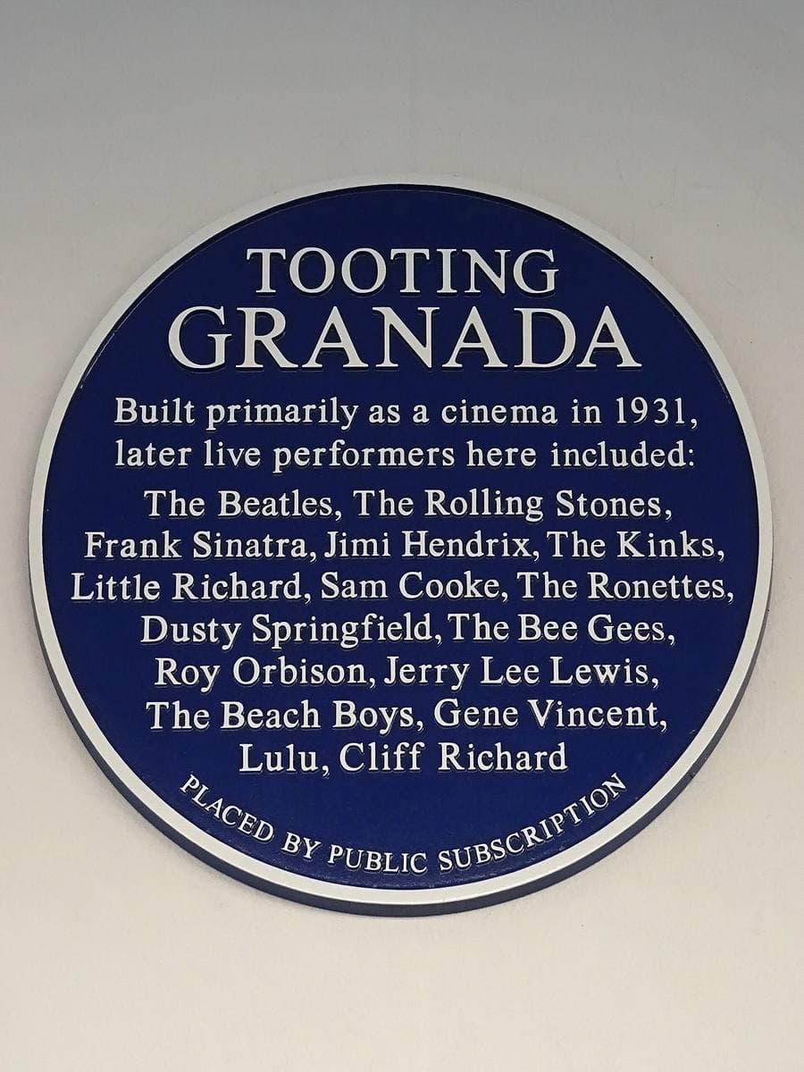 A round blue plaque listing performers at the Tooting Granada