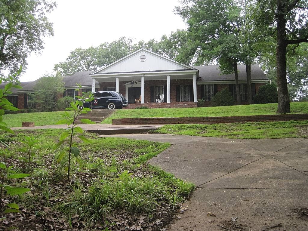 A white-columned ranch house up a lawn