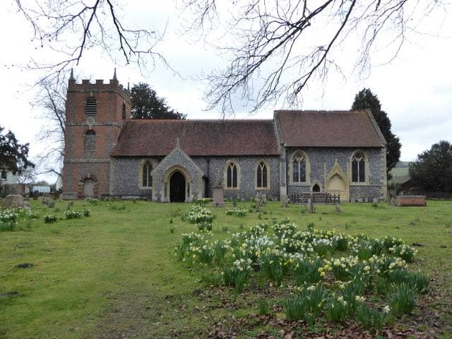 A flint and brick village church among trees