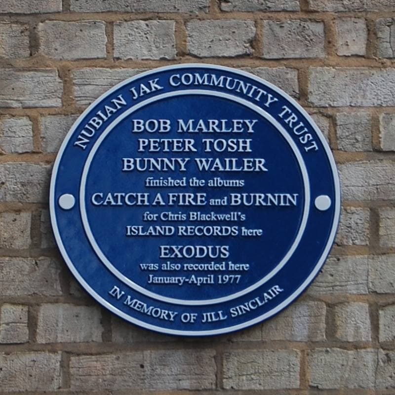 A round blue plaque on a brick wall