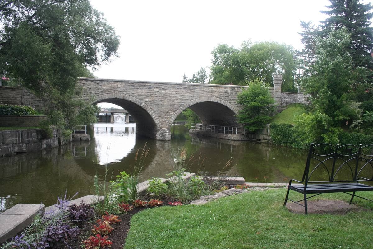 A stone bridge over the Avon river in Stratford, with gardens