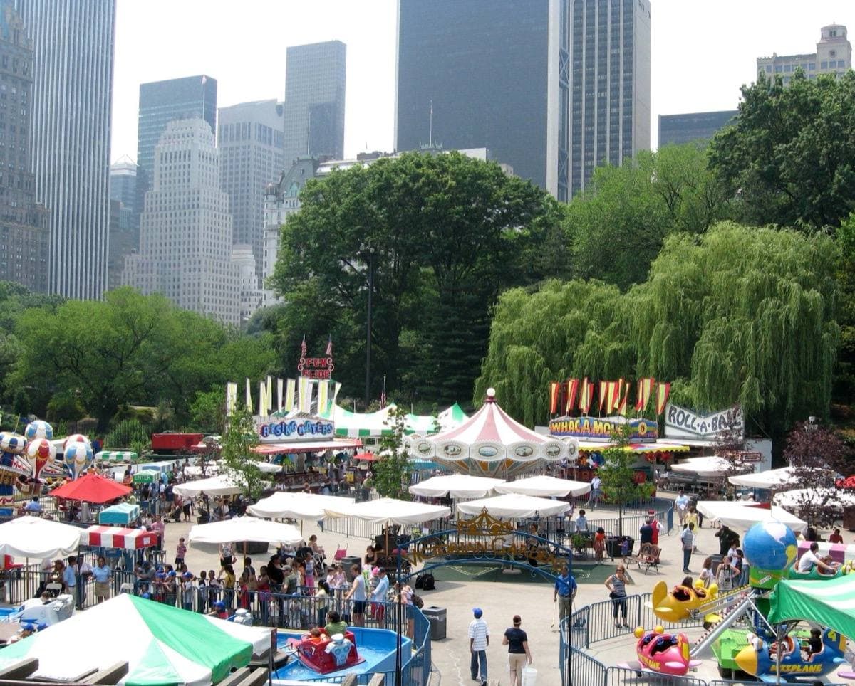 A summer funfair on Wollman Rink in Central Park with skyscrapers behind