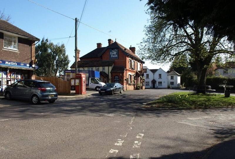 A village crossroads with a red-brick pub, a shop and a red telephone box