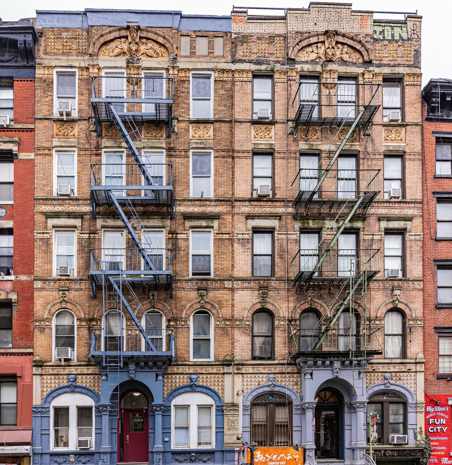 Two five-storey brick tenements with fire escapes and stoops on St Mark’s Place
