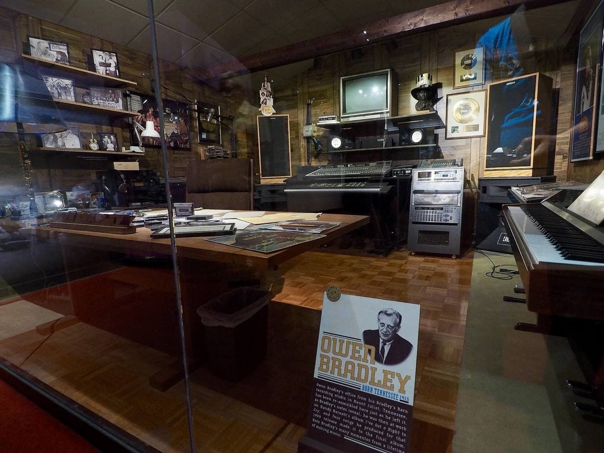 A wood-panelled office with a desk, chair and framed records on the walls, shown in a museum