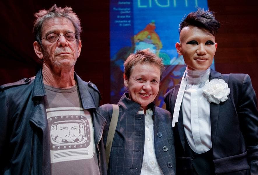 Lou Reed and Laurie Anderson standing with a young violinist in a white jacket