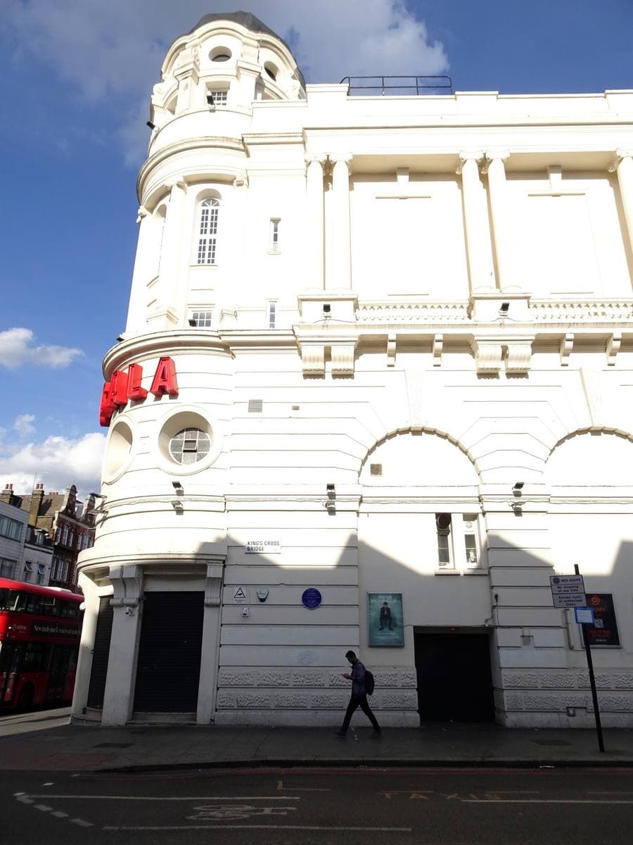 A white Edwardian corner building with a domed tower, seen from the street on a sunny day