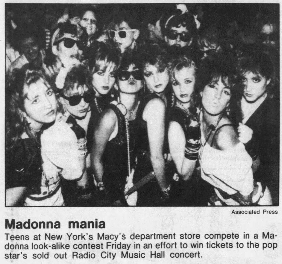 A crowd of teenage girls in lace, bows, crucifixes and dark glasses posing for a newspaper photograph
