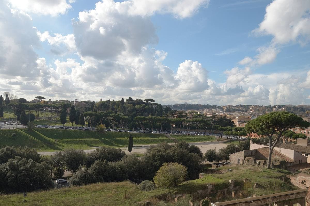 A long green valley under big clouds, the outline of an ancient racetrack, Rome beyond