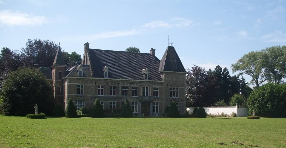 A turreted brick château behind a wide lawn in the Flemish countryside