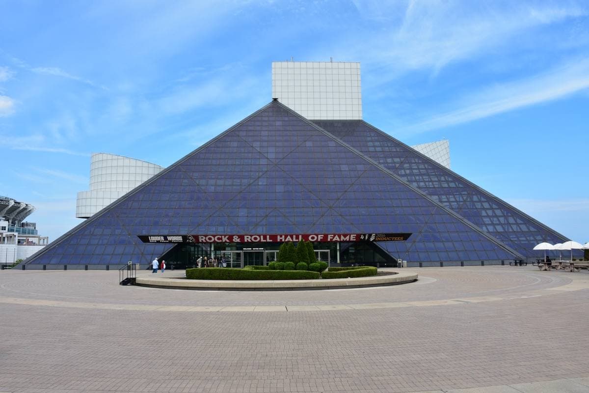 The glass pyramid of the Rock and Roll Hall of Fame on a wide plaza under a blue sky