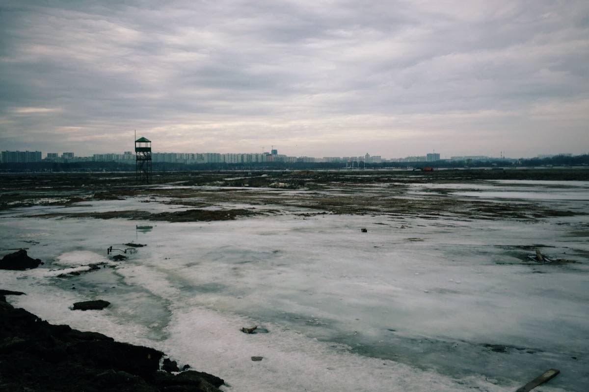 A wide flat field of snow and grass beside a new road in north-west Moscow