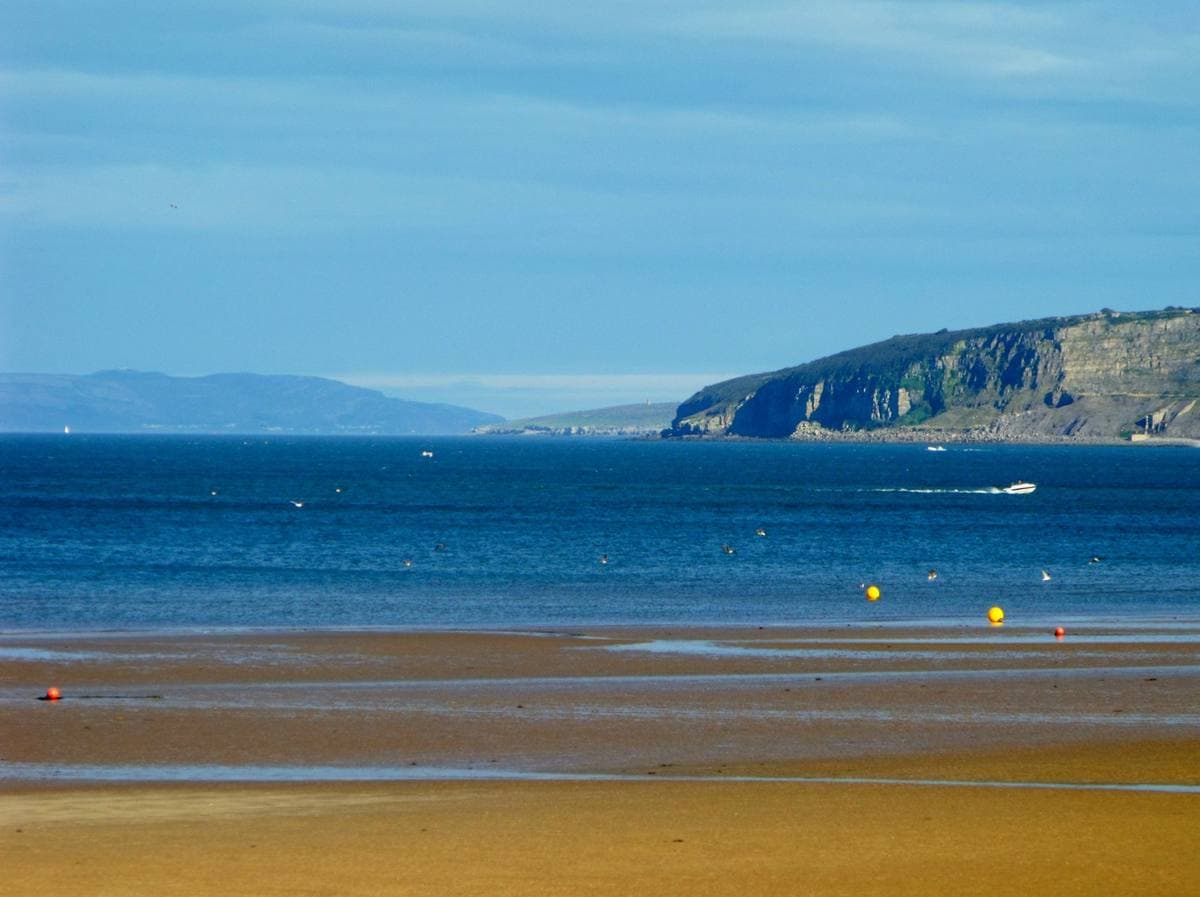 A wide sandy beach at Benllech with the headland behind