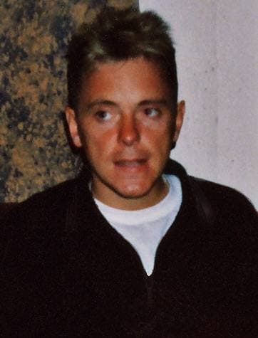A young man with short fair hair in a dark jumper, backstage