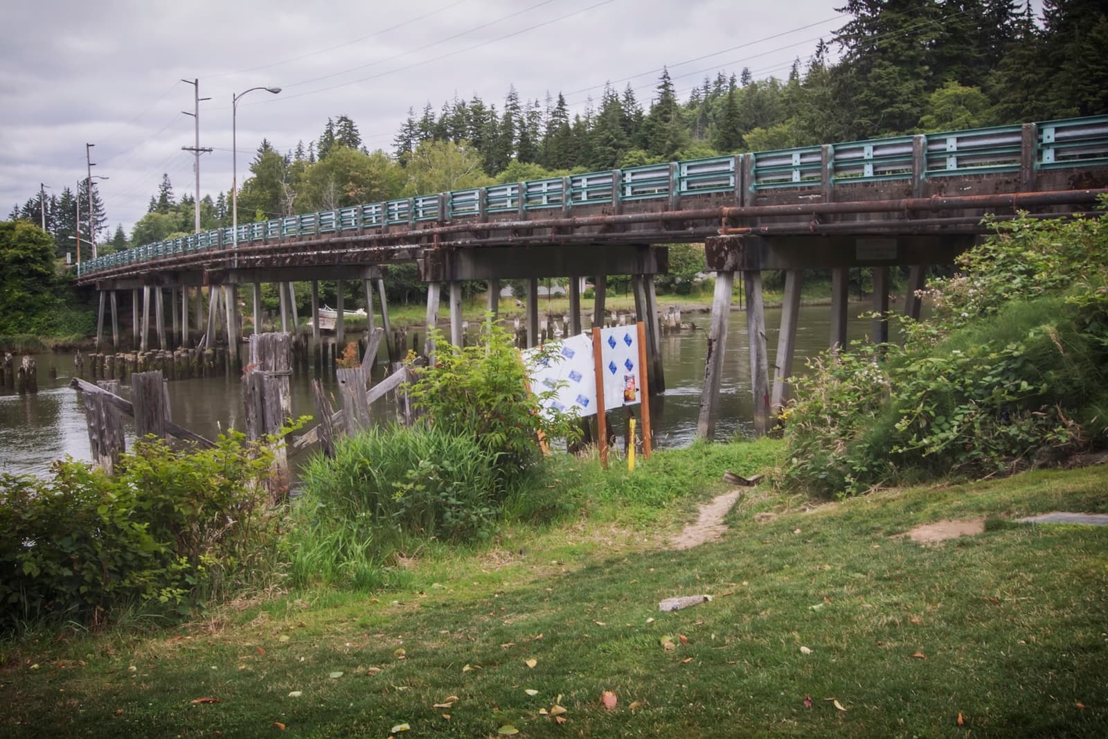 A low concrete road bridge over a brown river, with trees on the far bank