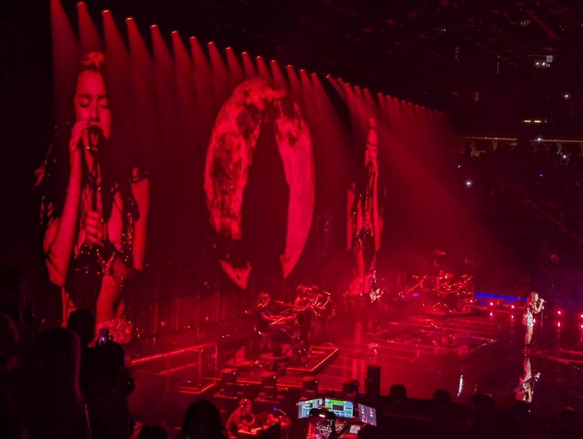 Olivia Rodrigo on a large arena stage under purple light