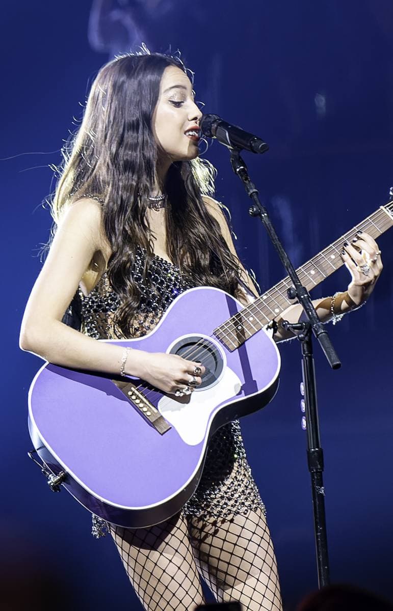 Olivia Rodrigo playing an electric guitar on stage