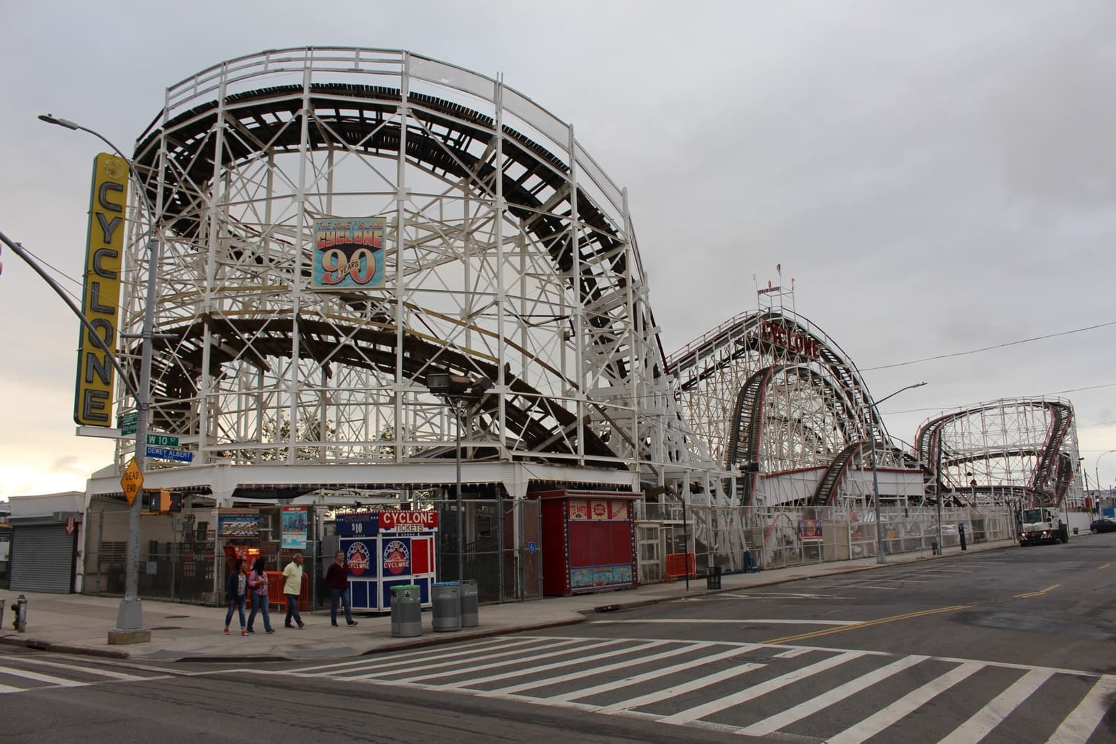 The white wooden lattice of the Cyclone roller coaster beside a street corner