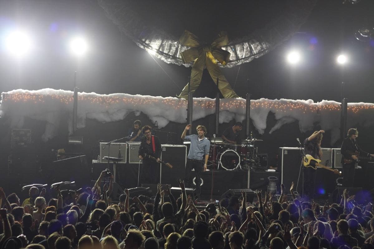 A wide arena stage under white lights, a crowd in front