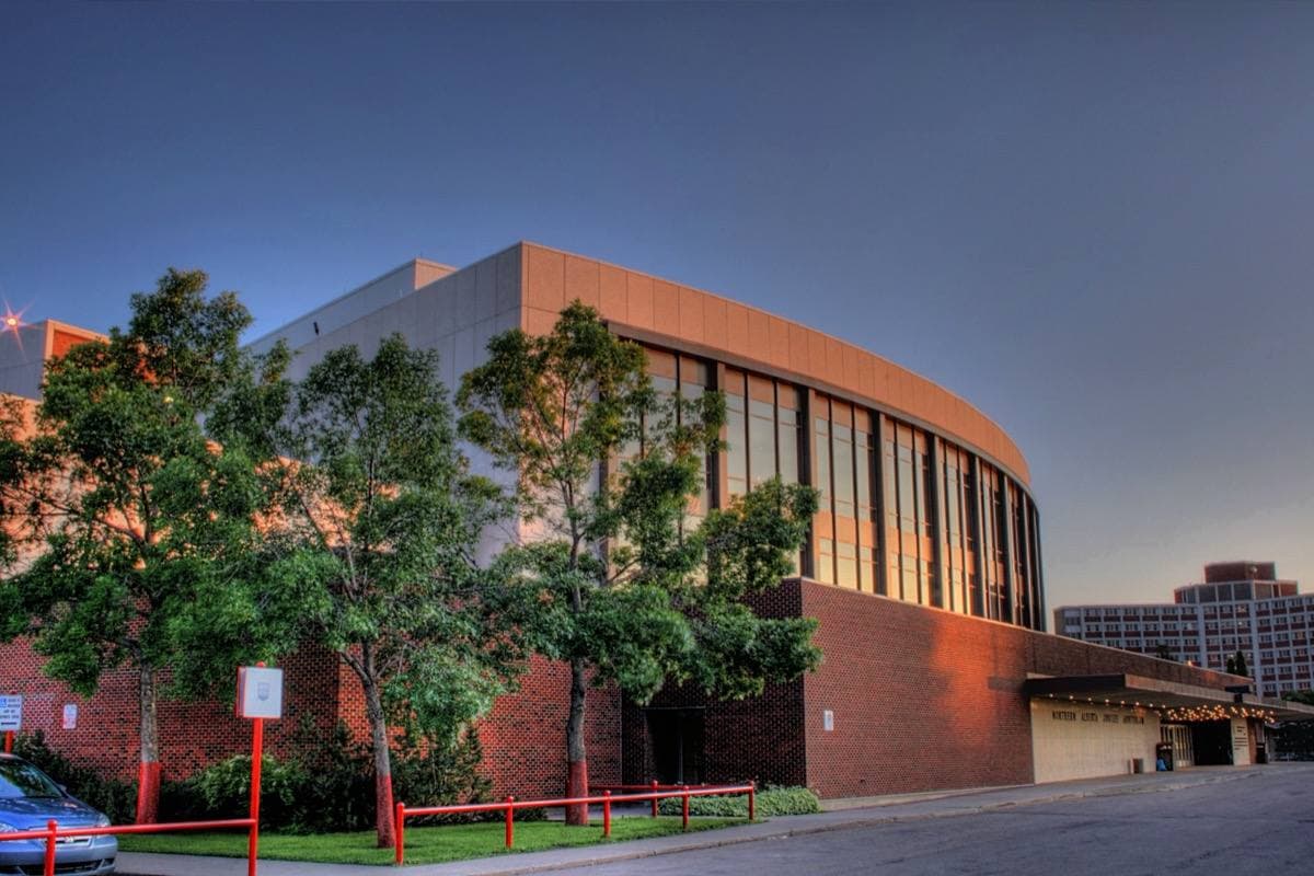 A long modernist concert hall with a glass front and lawn