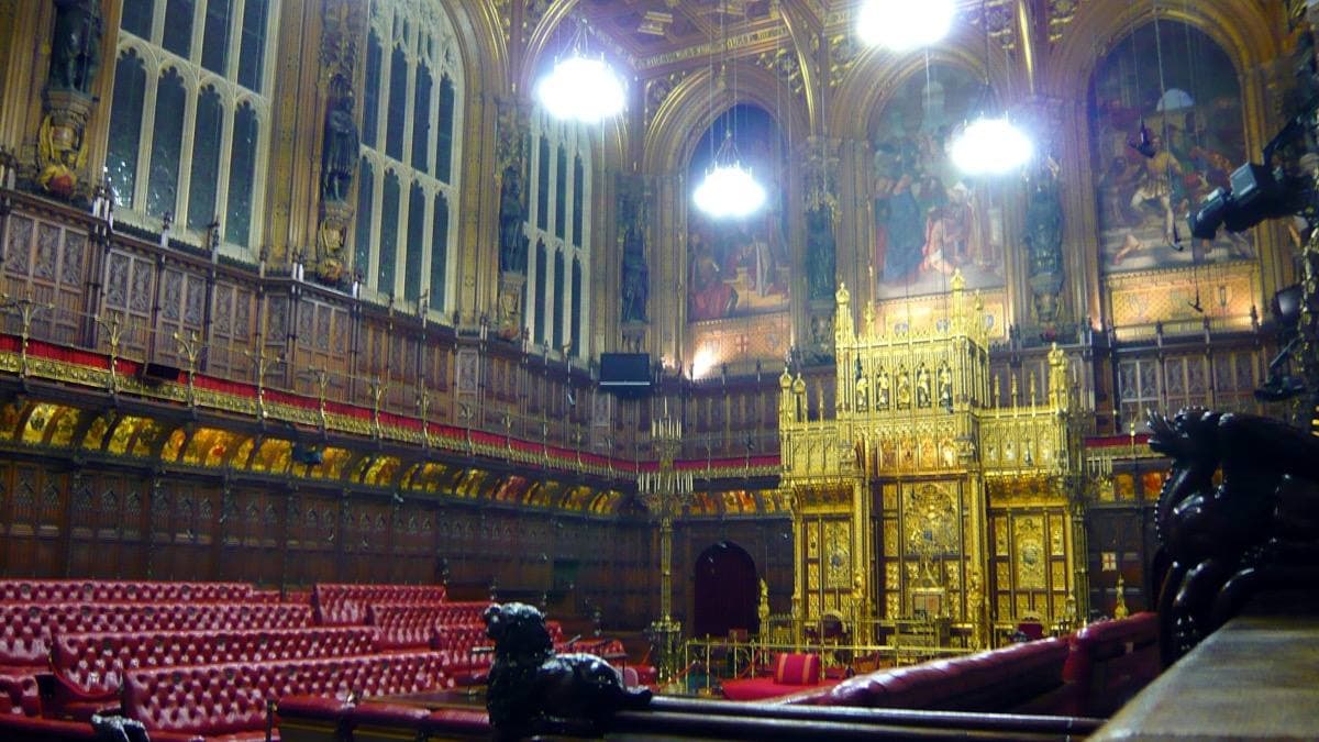A gilded chamber with red leather benches and a throne canopy