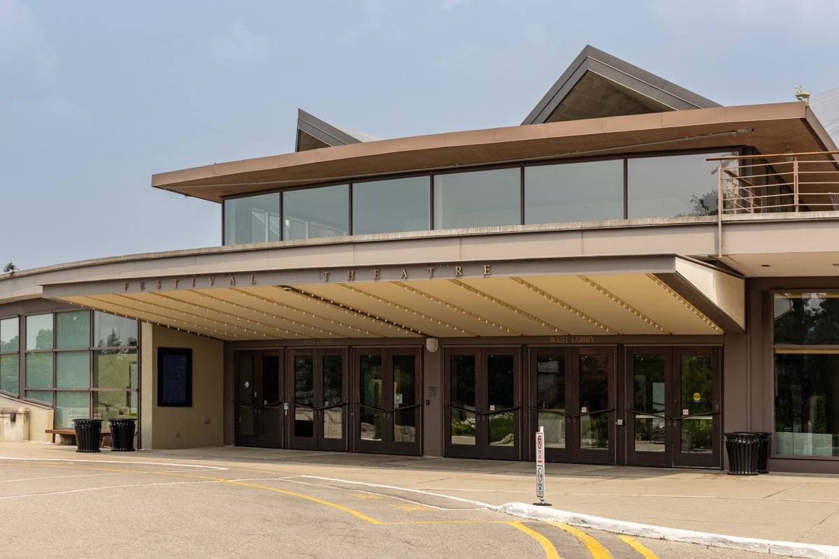 The west entrance of a round modern theatre with a crown-like roof
