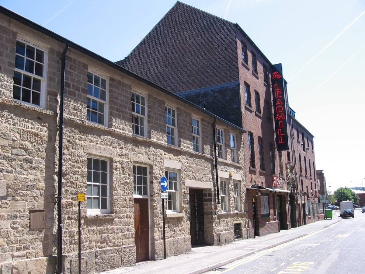 The Leadmill on Leadmill Road, Sheffield: a long stone mill building with a red vertical sign, on a quiet sunny street