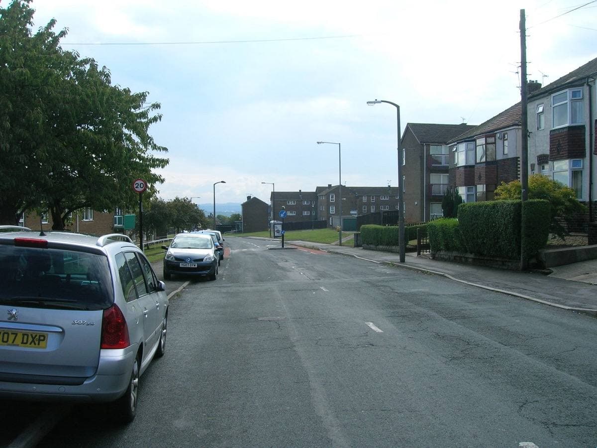 Stradbroke Road, Sheffield: a wide suburban road with parked cars, hedges and low blocks under a pale sky
