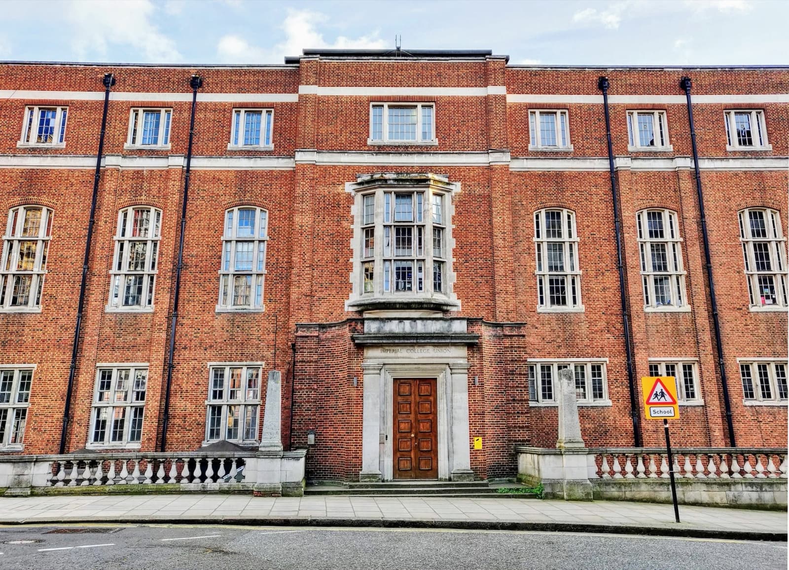 A red-brick college building behind railings