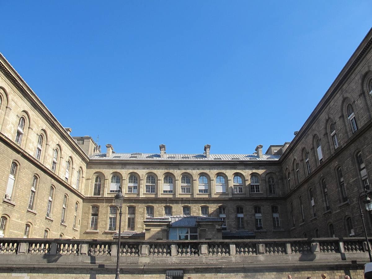 A long pale stone hospital building around a courtyard under a blue sky
