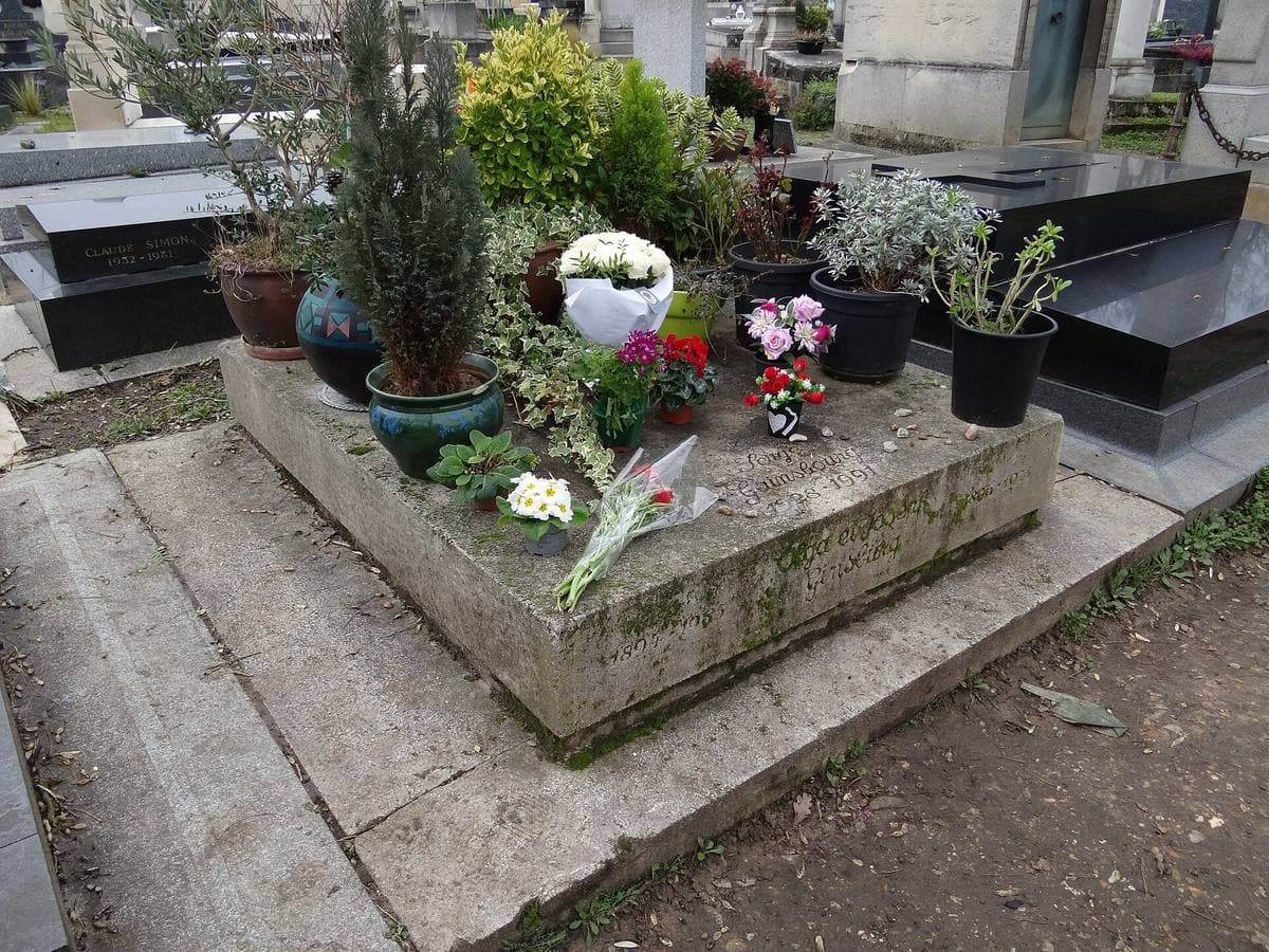 A low stone grave covered in pot plants, flowers and small offerings