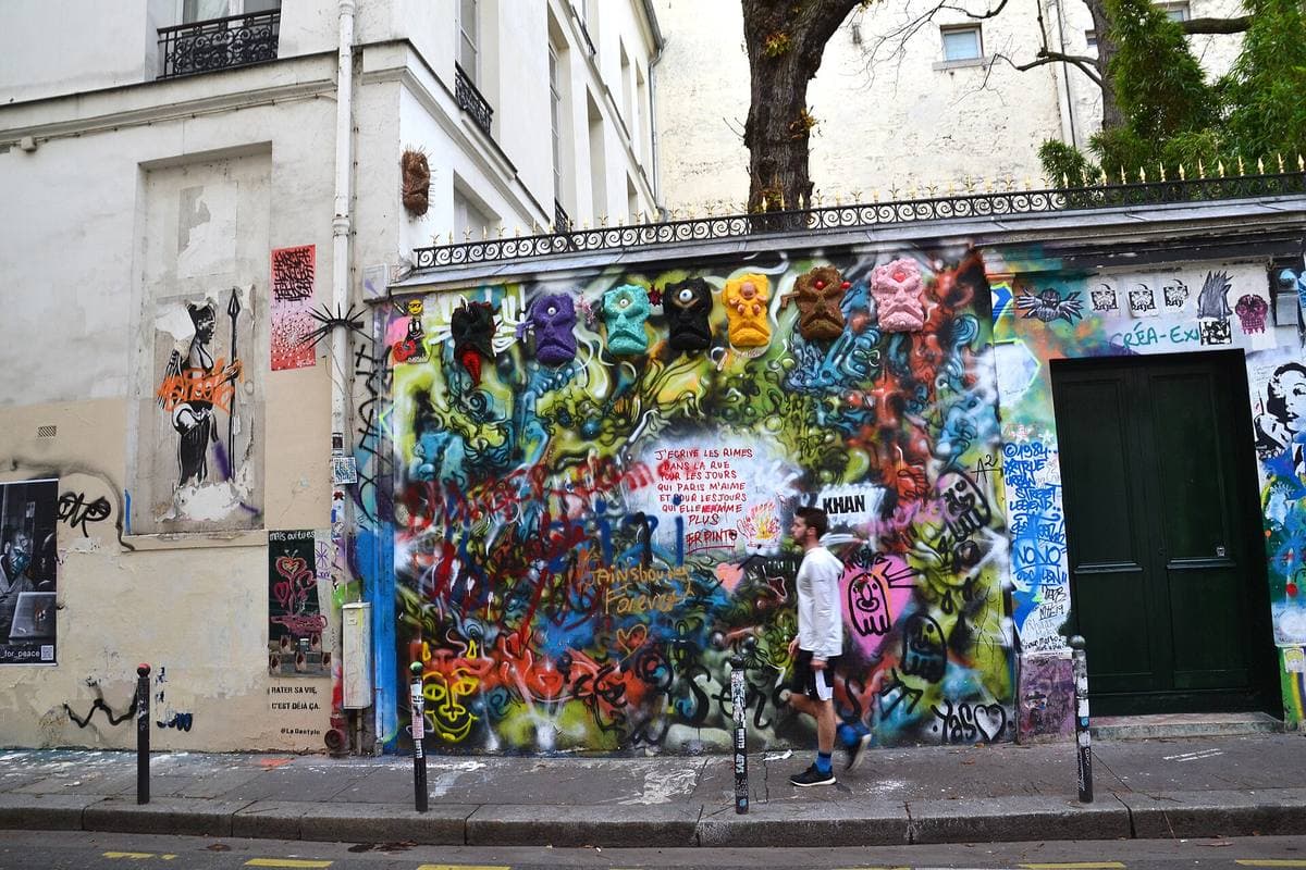 A long wall covered in colourful graffiti and portraits, with a green door