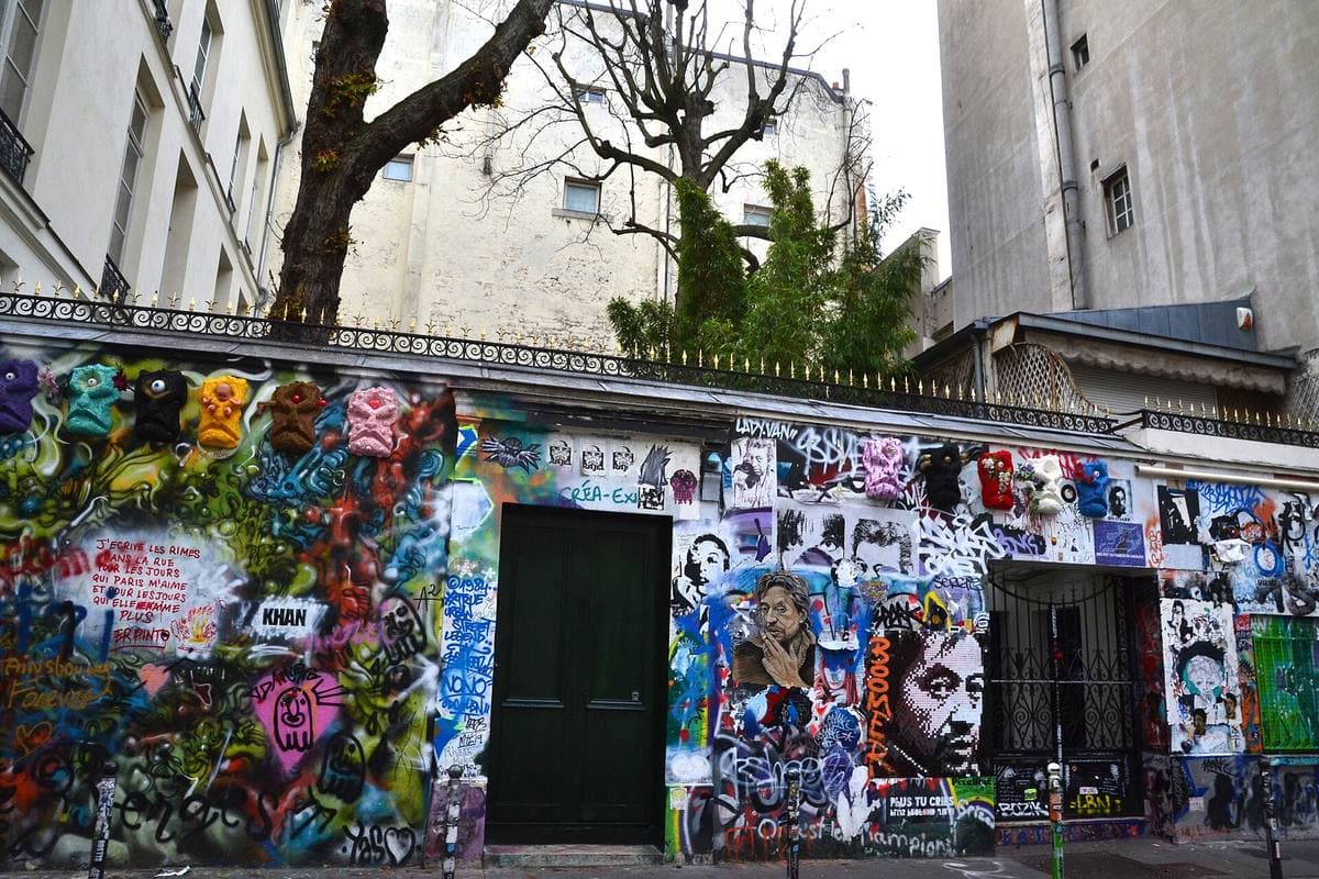 Close view of a graffiti-covered front with a barred window and a door, a woman in blue passing