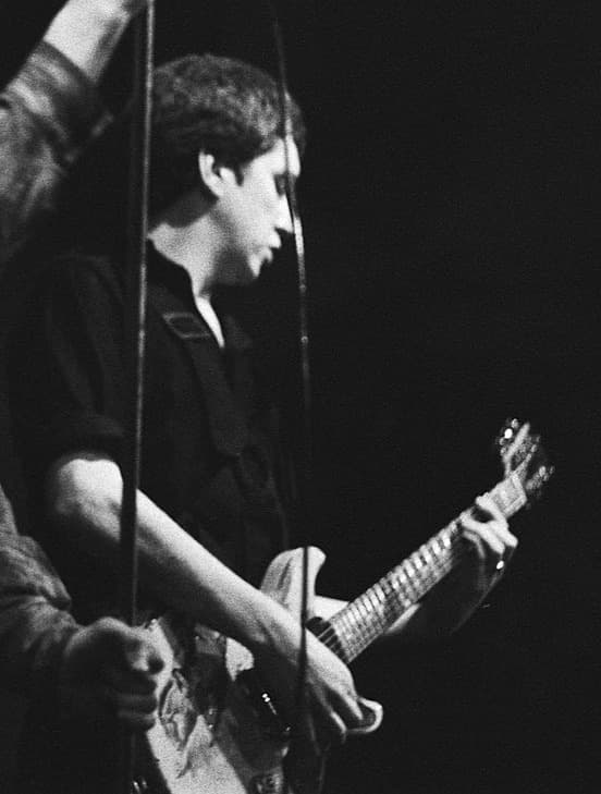 Steve Jones playing guitar, head down, black and white